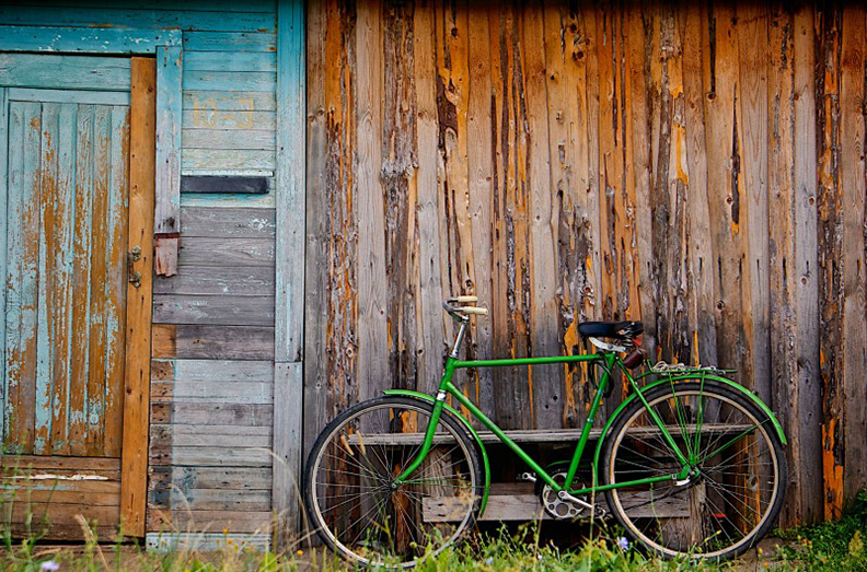 Ein grünes Fahrrad vor einer Holzhütte